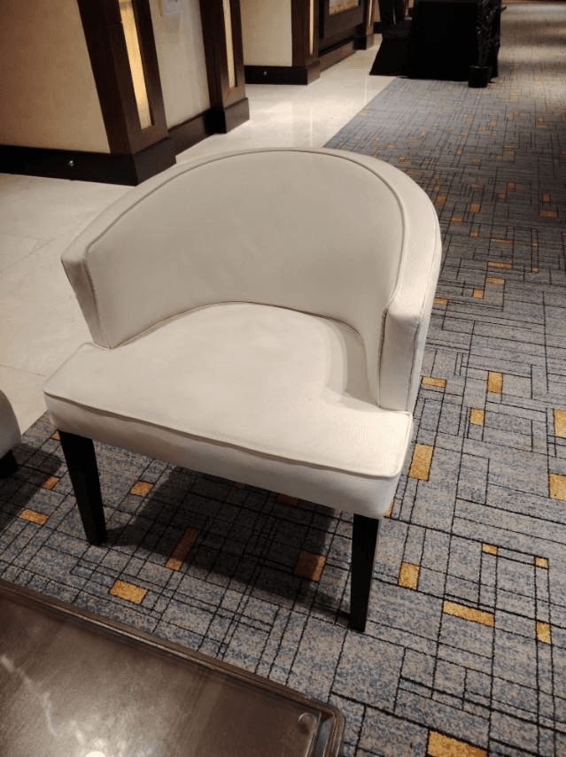 An off-white upholstered tub-style armchair with dark tapered legs and light grey contrasting piping. — 3D model