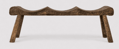A rustic bench made from dark, carved wood featuring a saddle-shaped seat and four splayed legs. — 3D model