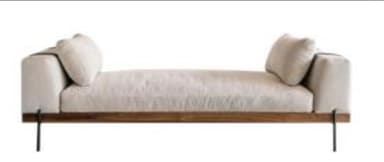 A modern daybed featuring a rectangular frame constructed from dark walnut wood, supporting a plush, off-white upholstered mattress. It includes two loose, rectangular armrest cushions and one loose rectangular backrest cushion, all in matching off-white fabric. The entire structure is elevated by four slender, black cylindrical metal legs. — 3D model