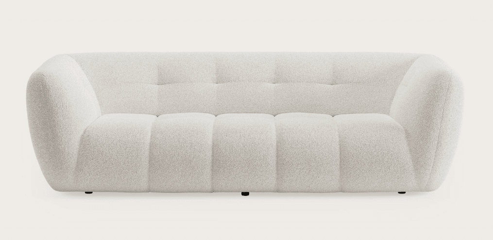A contemporary three-seater sofa upholstered in an off-white bouclé fabric. The design features a low profile, rounded arms and back, and distinctive channel-tufted seat cushions contrasting with button-tufted back cushions. The sofa sits on discreet black feet, contributing to its minimalist aesthetic. — 3D model