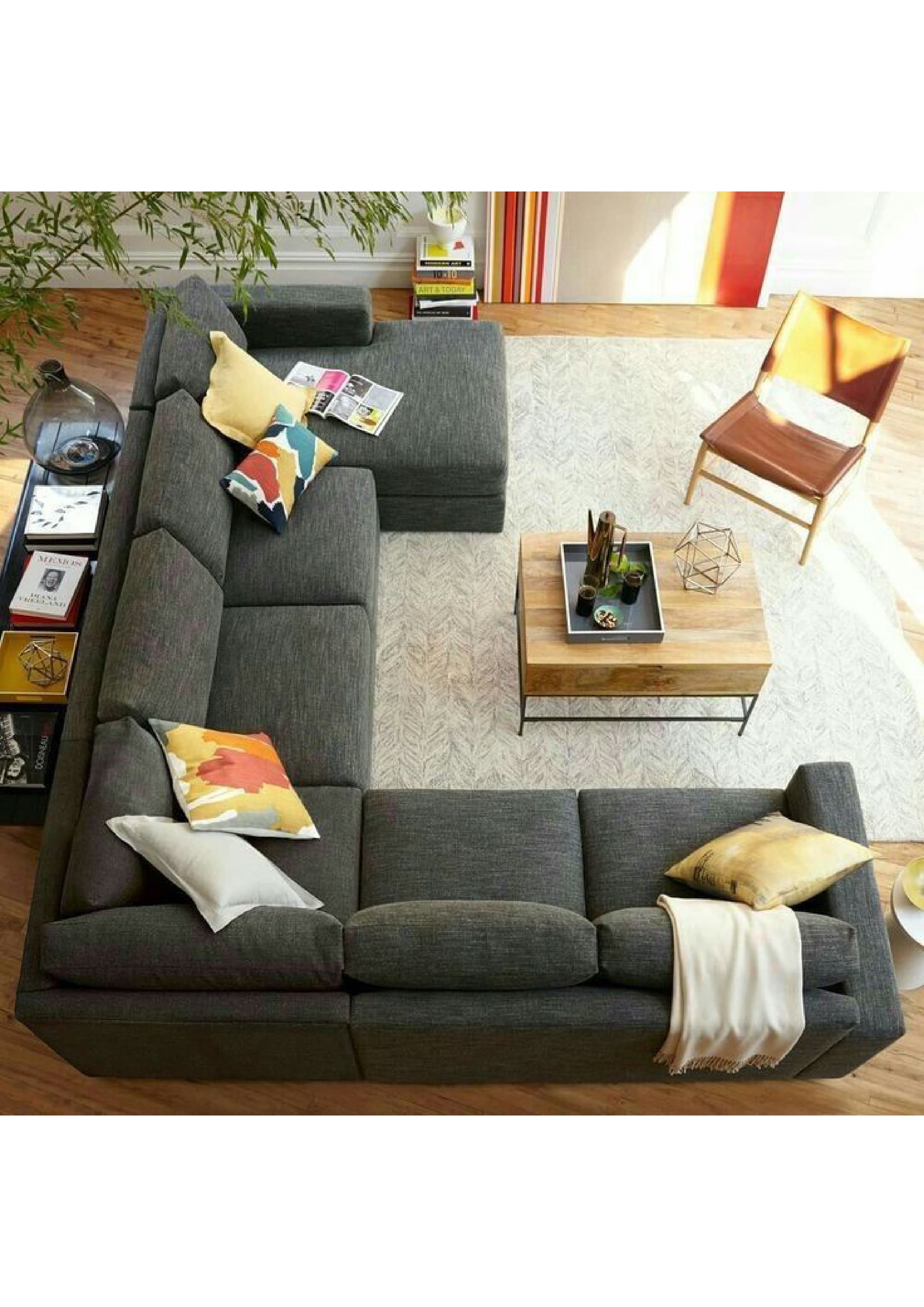 A large, contemporary L-shaped sectional sofa featuring a chaise lounge extension, upholstered in a textured gray fabric. The sofa consists of multiple modular components, including two two-seater sections and a chaise, arranged to form a spacious corner unit. It has a low-profile design with wide, flat arms and block-style legs. The backrests and seat cushions are plush, suggesting comfort. Several decorative throw pillows in various colors and patterns, along with a light-colored throw blanket, are placed on the sofa, adding accents to its neutral base. — 3D model