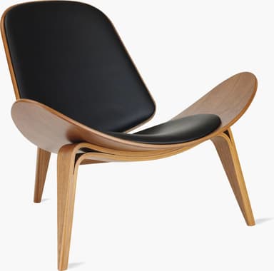 A high-quality image of a Hans J. Wegner CH07 Shell Chair, featuring a distinctive three-legged, curved plywood frame with black leather upholstered seat and back pads. The chair exhibits a light wood finish and a sleek, sculptural form against a white background. — 3D model