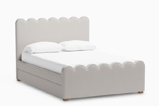 A bed frame with a scalloped headboard and footboard, upholstered in a light gray fabric. The frame has a built-in drawer or storage space below the mattress. It is supported by short wooden legs. — 3D model