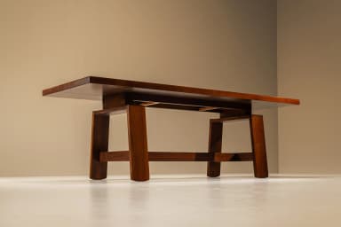 A large, rectangular solid wood table featuring a robust trestle base and a planked top. The top surface incorporates two flush-mounted rectangular covers, possibly for integrated power or cable management. The wood has a dark, rich finish. — 3D model