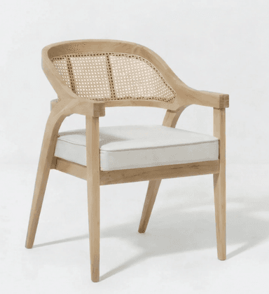 A light-toned wooden armchair featuring a curved cane backrest and a removable off-white upholstered seat cushion. The chair has a solid wood frame with straight legs and integrated armrests. — 3D model