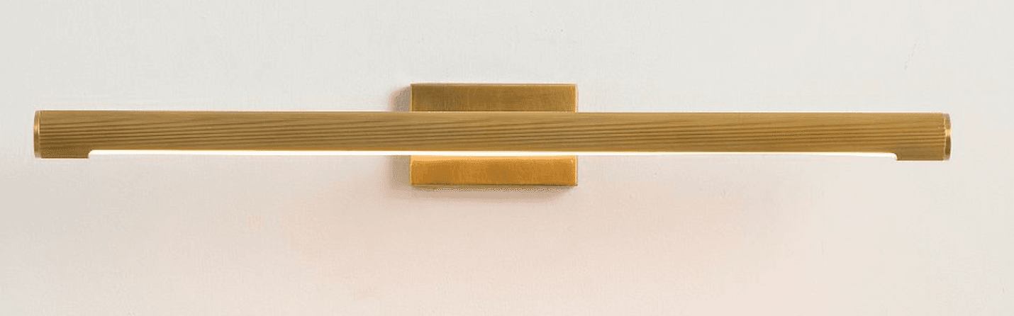 A horizontal, elongated wall-mounted LED light fixture, crafted from brass or a brass-toned metal. The main cylindrical body features a distinct ribbed texture and emits light from a continuous strip along its bottom edge. It is affixed to the wall by a rectangular mounting plate, creating a minimalist and functional aesthetic. — 3D model