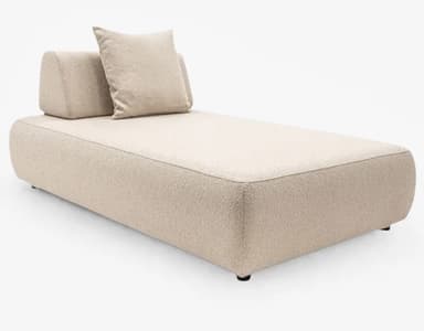 A modern daybed featuring a minimalist design. It is upholstered in a light beige, textured boucle fabric, with distinct piping along the edges. The base is long and rectangular with softly rounded corners. At one end, there is a large, loose back cushion and a smaller, square throw pillow, both matching the main upholstery. The daybed sits on small, discreet dark feet. — 3D model