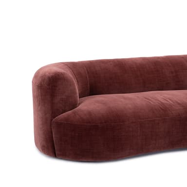 A contemporary curved sectional sofa upholstered in a rich, russet-toned velvet fabric. The sofa features a low-profile, modular design with gently rounded edges and continuous, integrated armrests and backrests. Its sinuous form is composed of at least two connected sections, creating an inviting and cohesive seating arrangement with no visible legs, resting directly on the floor. — 3D model