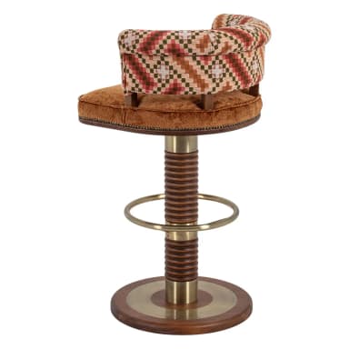 A swivel bar stool featuring a round upholstered seat in brown velvet and a curved, rolled backrest upholstered in a multi-patterned fabric. The central column consists of a brass top and bottom section flanking a distinctive ribbed or spiral-cut wooden segment. A circular brass footrest is integrated into the column, which rests on a round wooden base with a central brass inlay. — 3D model