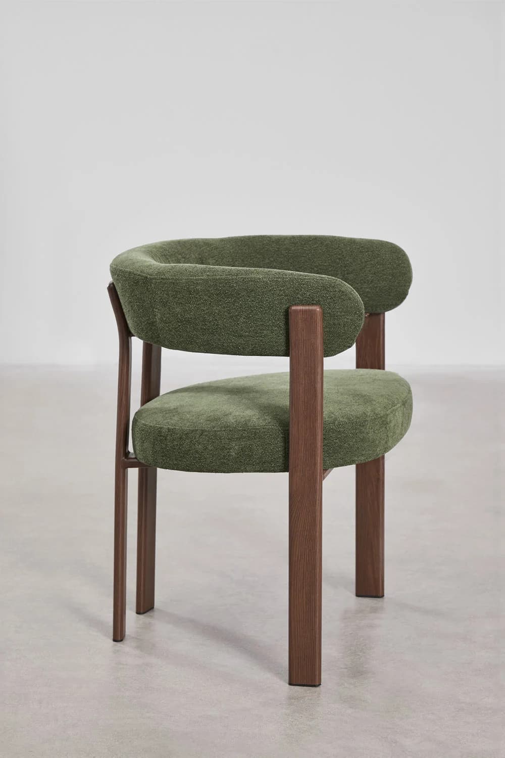 A modern accent chair featuring a curved upholstered backrest and seat in a textured green fabric. The chair has a visible wooden frame with four legs and armrests constructed from dark stained wood. The design is minimalist with clean lines. — 3D model