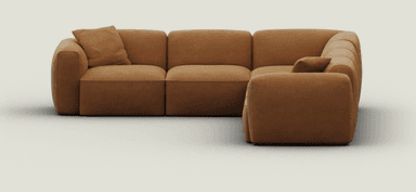 An L-shaped, modular sectional sofa upholstered in a warm camel brown microsuede-like fabric. The sofa features a soft, rounded profile with plush, integrated seat and back cushions. It consists of multiple segments, including corner and armrest pieces, creating a cohesive, inviting seating arrangement. The design is low-slung and minimalist, emphasizing comfort. — 3D model