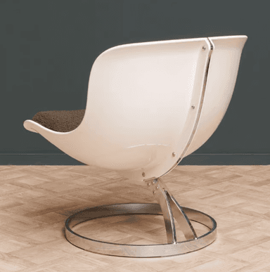 A modern armchair featuring a white molded shell seat and back, with a thick, textured green cushion. The chair is supported by a chrome-plated metal base with a circular pedestal and a curved upright structure connecting to the seat. — 3D model