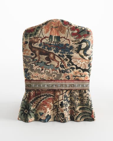 A fully upholstered side chair with a high, curved back and a skirted base. The chair is covered in a richly patterned textile that features floral motifs, figures, and possibly animal forms. A decorative band with intricate patterns separates the upper upholstery from the skirted lower portion. The overall aesthetic suggests a historical or antique piece. — 3D model