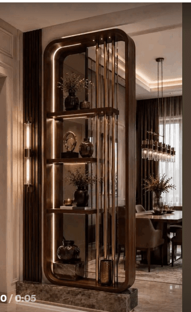 A luxurious room divider featuring a gold-toned metal frame, intricately designed with arched sections and vertical fluted glass panels. One side incorporates multiple integrated display shelves, each illuminated by warm LED strips, showcasing decorative objects. The divider serves to visually separate a living space while maintaining an open feel. — 3D model