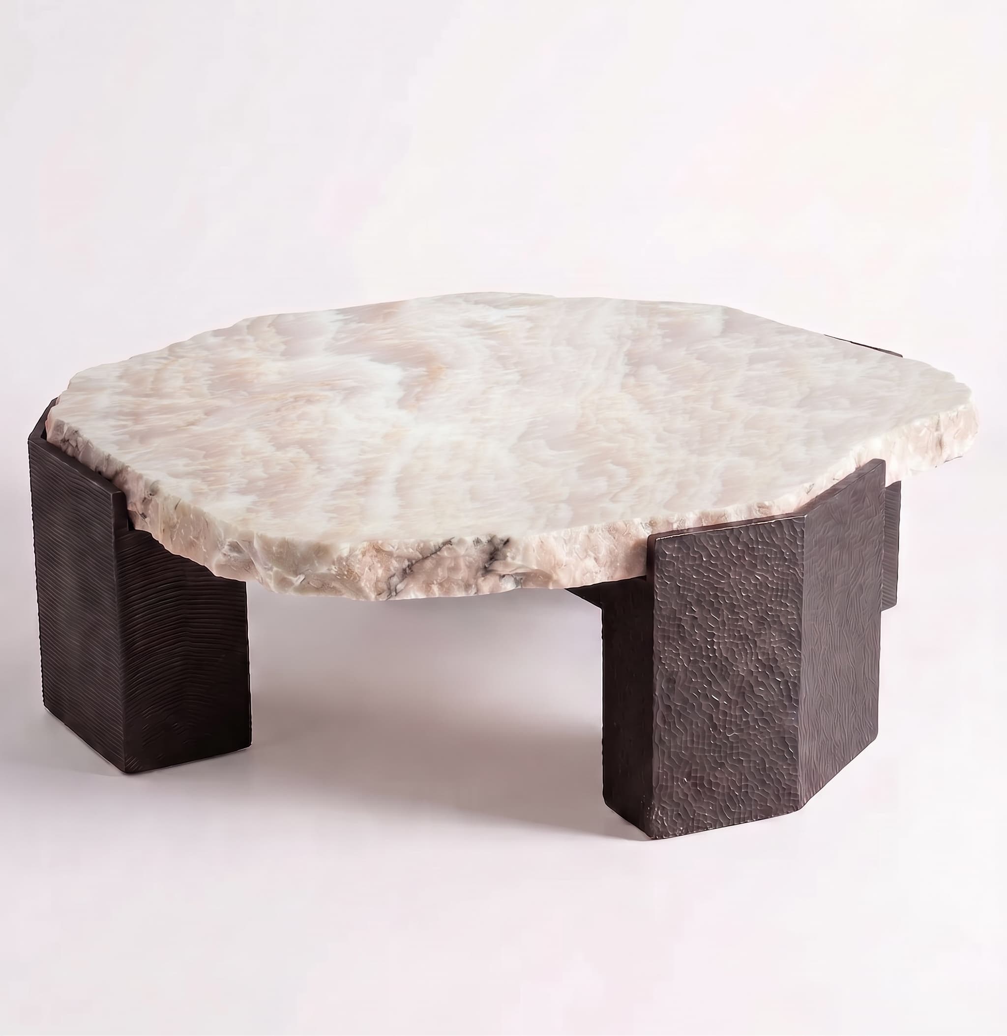 A low-profile coffee table featuring a thick, organically shaped tabletop made from light-colored onyx with natural veining and rough, unpolished edges. The top rests upon four substantial, rectangular block legs made of a dark, textured material, possibly cast metal or resin, giving the table a robust and earthy aesthetic. — 3D model