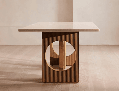 A long, rectangular dining table featuring a light-colored travertine top with rounded corners. The top is supported by two substantial, medium-toned wooden pedestal bases. Each base is characterized by vertical fluting or reeding and a large, semicircular cutout on its inner side, creating a sculptural and architectural aesthetic. — 3D model
