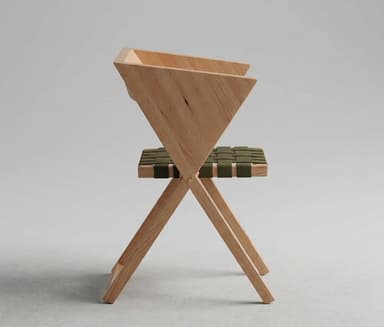 A minimalist folding chair featuring a light-toned wooden frame and an olive green woven webbing seat and backrest. The chair is depicted in a partially open or folded state, suggesting its space-saving design. Its clean lines and simple construction highlight a modern aesthetic. — 3D model