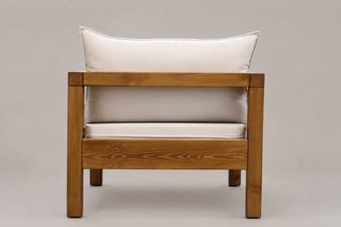 A sturdy armchair featuring a robust wooden frame and plush, light-colored cushions for seating and back support. The design is rectilinear and minimalist. — 3D model