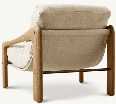 A contemporary lounge chair featuring a prominent, sculptural wooden frame with integrated armrests, supporting a deep-seated, upholstered cushion system. The frame is crafted from light-toned wood with a visible grain, possibly oak or ash, and has rounded edges. The seat and backrest are composed of thick, plush cushions upholstered in a cream or off-white bouclé fabric, providing a soft, textured contrast to the smooth wood. The design emphasizes comfort and a minimalist yet inviting aesthetic. — 3D model