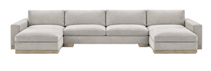A large, contemporary U-shaped sectional sofa featuring light grey fabric upholstery and a low-profile wooden plinth base. It is composed of multiple modules, including a central two-seat armless section and two chaise lounge sections on either end, creating a symmetrical layout. The cushions are generously proportioned, and the design is characterized by clean lines and a minimalist aesthetic. — 3D model