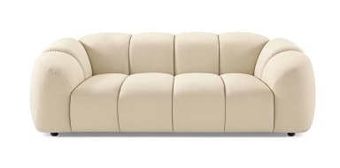 A contemporary sofa with a plush, channel-tufted design. The sofa features rounded, organic shapes with vertically segmented cushioning on the back and seat. It has integrated armrests that flow seamlessly into the backrest and a low profile. The piece is upholstered in a soft-touch fabric and rests on small, dark-colored legs. — 3D model