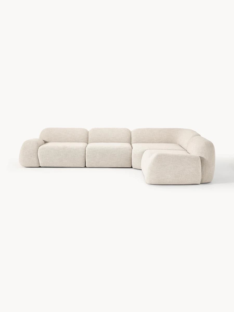 A contemporary modular sectional sofa upholstered in light beige textured fabric, featuring soft, rounded edges and a low-profile design. The configuration includes multiple seat modules and an extended chaise section, forming an L-shape. — 3D model