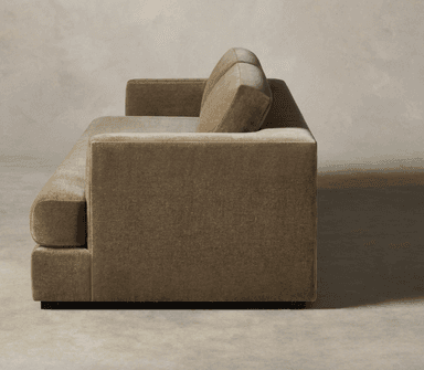 A contemporary two-seater sofa upholstered in a plush, olive green velvet or similar fabric, featuring a low-profile design, track arms, two distinct loose back cushions, and a single, long seat cushion. The sofa rests on discreet, recessed block feet, giving it a floating appearance. — 3D model