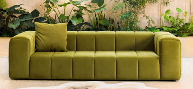 A long, low, rectangular furniture piece, upholstered in an olive green velvet-like fabric. It features consistent vertical channel tufting across its entire visible surface, including the deep seating area and all side panels. The piece has a sleek, block-like form, appearing to sit directly on the floor with no visible legs. A single matching square throw pillow is included, positioned on one end of the daybed. — 3D model