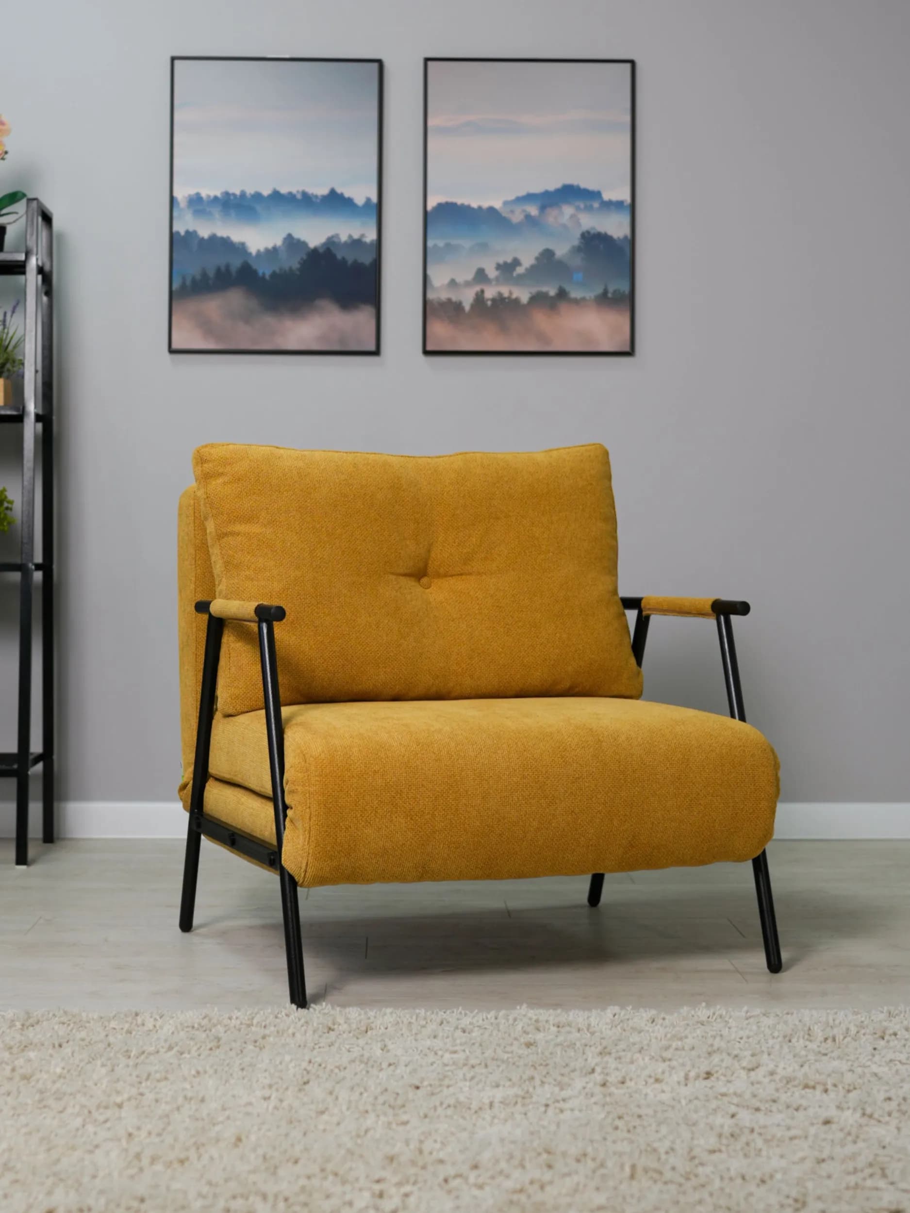 A modern upholstered armchair featuring a bright yellow fabric and a minimalist black metal frame. The chair has a comfortable, button-tufted back cushion and a thick, layered seat cushion. The metal frame extends to form slender armrests, partially covered with a lighter-colored wrap. The design incorporates a mechanism that suggests it may be convertible, possibly into a bed, given the layered structure beneath the seat. Its overall aesthetic is contemporary and functional. — 3D model