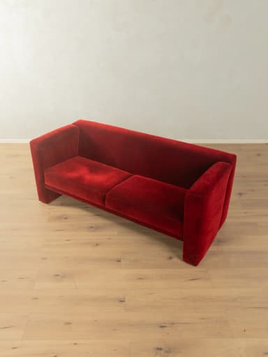 A two-seater sofa with a distinct geometric design. It features deep red velvet upholstery, high, angular armrests that extend downwards to form the base, and a single seat cushion. — 3D model