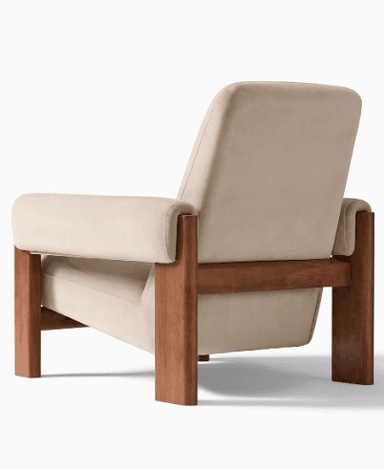 A single armchair with a wooden frame and upholstered cushioning. The armchair has a reclined backrest, wide armrests, and a seat cushion. The wooden frame appears to be constructed from solid wood with a warm brown finish, forming the legs and structural supports. The upholstery is a light beige or cream color, with a soft texture visible. — 3D model