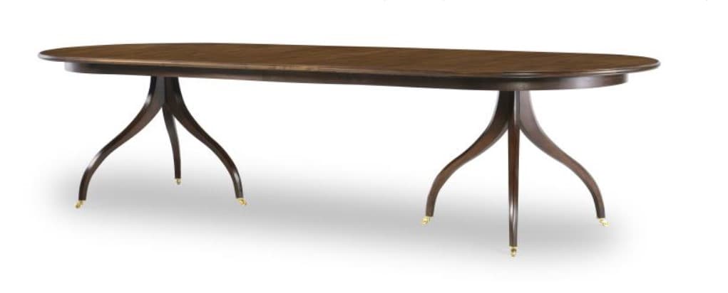 An oval dining table with a dark wood finish. The table is supported by two pedestal bases, each with three splayed legs. The legs have curved, organic forms and are capped with small brass sabots. — 3D model