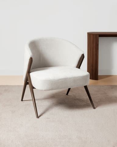 A modern armchair with a rounded back and seat, upholstered in a textured off-white fabric. The frame and legs are made of dark wood, featuring an angular, open design that supports the upholstered shell. — 3D model