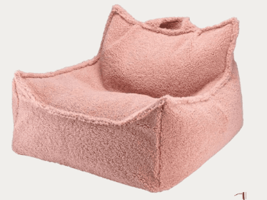 A pink, low-profile, single-person seating unit, appearing to be a structured bean bag chair. It features a soft, textured, teddy fleece or boucle fabric. The backrest is shaped with two distinct points, resembling cat ears or a crown, and it has integrated side supports that function as armrests. The overall shape is inviting and plush. — 3D model
