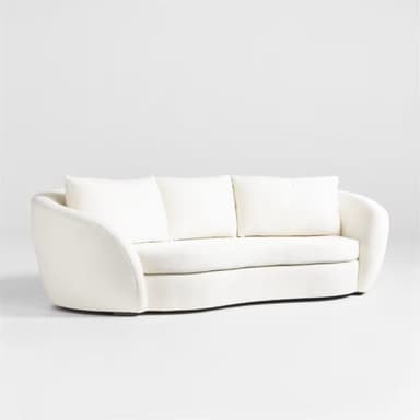 A modern three-seater sofa with a curved silhouette and plush upholstery. It features three loose back cushions and a continuous seat cushion. The arms are rounded and integrated into the overall curved design. The upholstery appears to be a textured fabric, possibly boucle or sherpa, in a light cream color. — 3D model