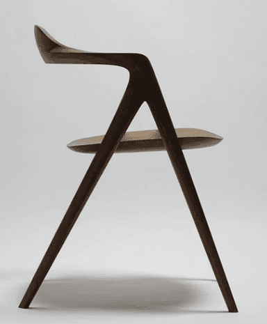 A modern wooden chair with a curved backrest and seat. The chair features a four-legged base with tapered legs and integrated armrests that flow seamlessly into the backrest. The design emphasizes organic curves and a minimalist aesthetic. — 3D model