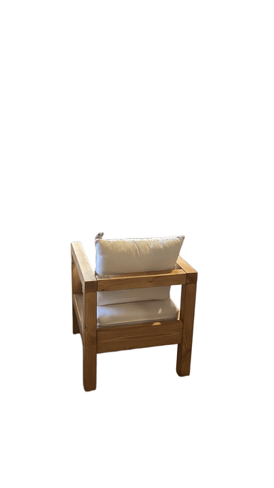 A wooden armchair with white cushions. The frame is constructed from thick, natural-toned wooden beams. It features a wide seat and backrest, both upholstered with thick white cushions. A lumbar pillow is also present on the backrest. The design appears robust and suitable for outdoor or rustic indoor settings. — 3D model