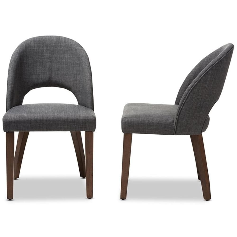 A contemporary dining chair upholstered in dark gray fabric, featuring a curved backrest with a distinct lower back cutout, supported by four tapered dark brown wooden legs. The image shows two chairs, one from the front and one from the side, highlighting their modern design. — 3D model
