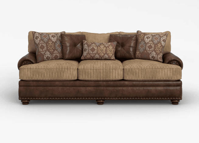 A three-seater sofa featuring a robust design with a mixed upholstery of dark brown leather and beige textured fabric. It has rolled arms accented with decorative nailhead trim, and a three-over-three cushion configuration. The seat cushions are upholstered in a light beige fabric, matching the back cushions, while the frame and arms are finished in a rich dark brown leather. Several accent pillows are present, some in solid brown leather and others with a geometric, Southwestern-inspired pattern in muted reds, browns, and grays. — 3D model
