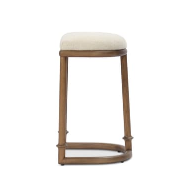 A transitional style bar stool featuring a solid wood frame with a light brown finish and a rectangular, generously padded upholstered seat in a cream-colored, textured fabric. The stool has four subtly tapered legs with decorative turned details near the bottom, connected by a curved, arched footrest for support. — 3D model