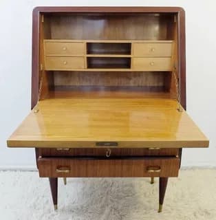 A Mid-Century Modern secretary desk featuring a drop-front writing surface that reveals internal compartments. The desk is constructed from dark and light toned wood, with slender, tapered legs tipped with brass caps. The interior features small drawers and open cubbies, while the exterior has two larger drawers below the writing surface, all fitted with minimalist brass pull handles. The overall design exhibits clean lines and a functional yet elegant aesthetic characteristic of the mid-20th century. — 3D model
