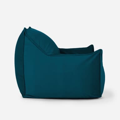 A teal-colored bean bag chair with a structured, armchair-like design. It features a high backrest, integrated armrests, and a deep seat, all upholstered in a soft, textured fabric. The chair appears to be filled with loose material, allowing it to conform to the user's body. A small red tag with white lettering is visible on the upper right side of the backrest. — 3D model