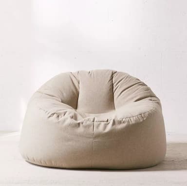 A single modern bean bag chair with a smooth, soft textile covering in a light beige or off-white color. The chair has a typical pear-like or teardrop shape, designed to conform to the user's body. It appears plump and well-filled, with subtle folds indicating the flexible nature of its construction. The simple design emphasizes comfort and casual seating. — 3D model