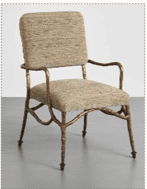 An armchair featuring a distinctive artisan-forged metal frame with an organic, branch-like texture and an antique bronze or copper finish. The seat and backrest are upholstered in a textured, neutral-toned fabric, providing a contrast to the rugged metal frame. The chair has integrated armrests formed by the continuous metal structure, and its legs terminate in small, decorative feet. — 3D model