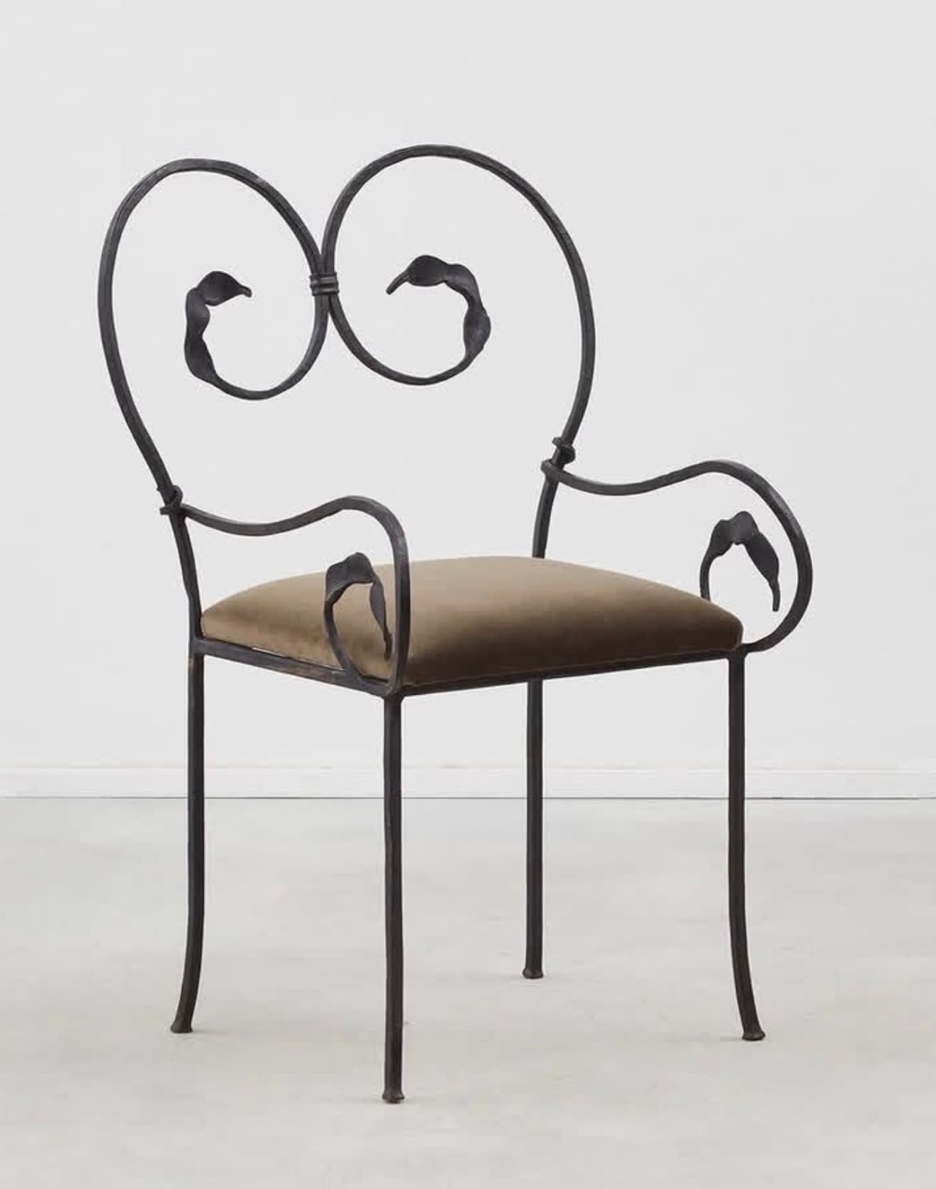 An ornate armchair featuring a dark, possibly wrought iron, frame with intricate scrollwork and leaf motifs on the backrest and armrests. It has a plush, olive green velvet upholstered seat cushion and four slender, slightly curved legs. — 3D model