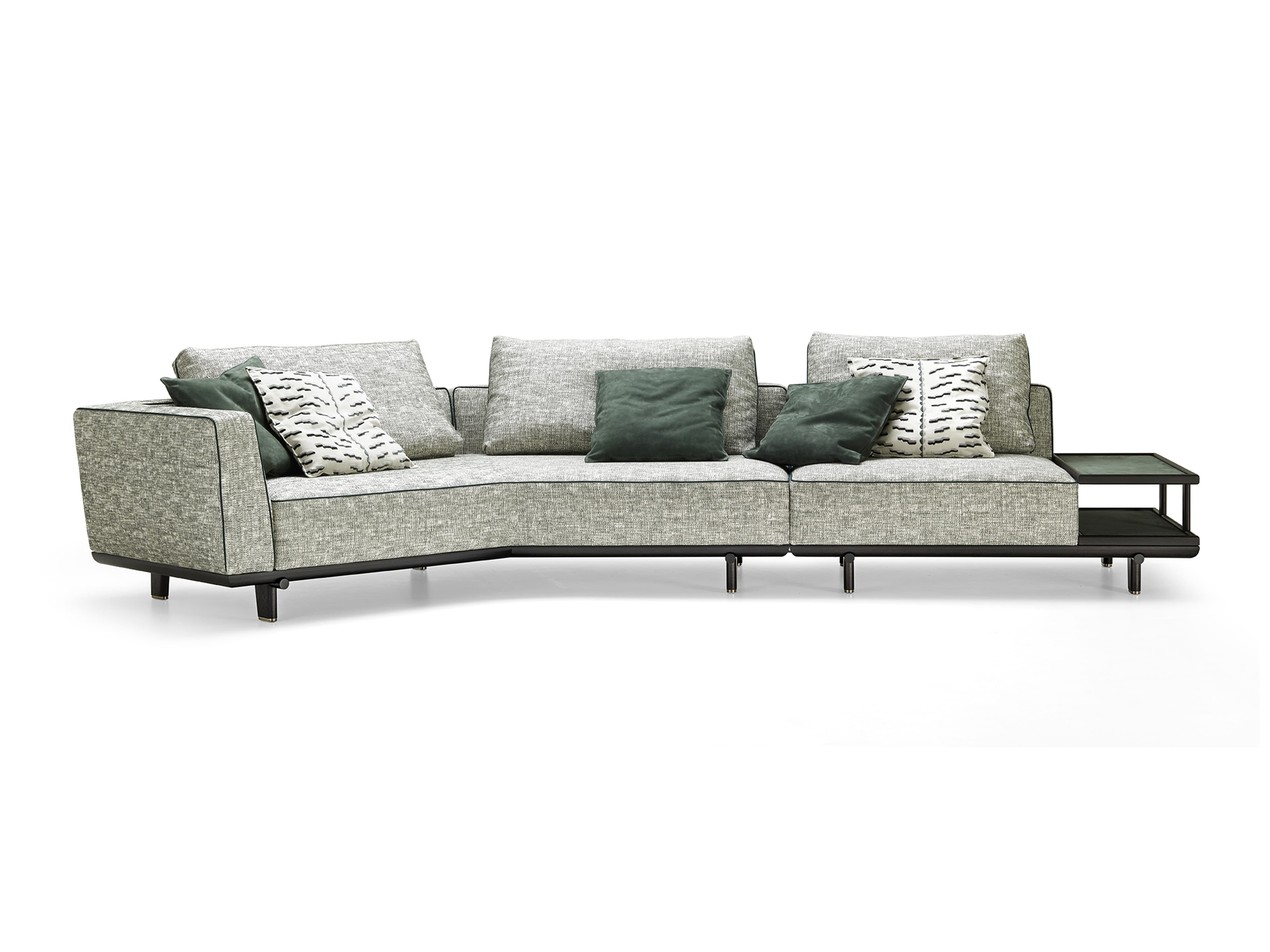 A modern L-shaped sectional sofa featuring a light grey-green textured fabric upholstery and an exposed dark metal frame. The sofa includes multiple back cushions and a variety of accent pillows in solid dark green and a black-and-white abstract pattern. An integrated side table with a dark finish and an upper glass or laminate surface extends from one end of the sofa. — 3D model