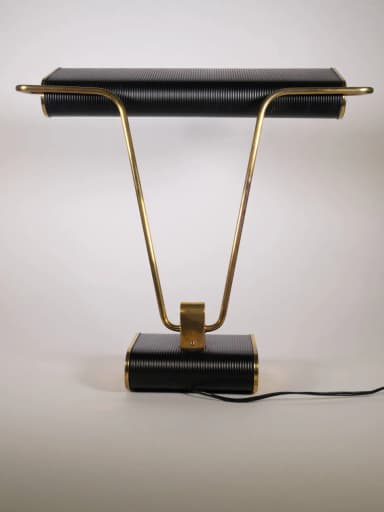 A stylish mid-century industrial desk lamp featuring a horizontal, rectangular, ribbed black shade and a matching ribbed black rectangular base. It is supported by two V-shaped polished brass arms that connect the shade to the base, with a central brass accent bracket. — 3D model