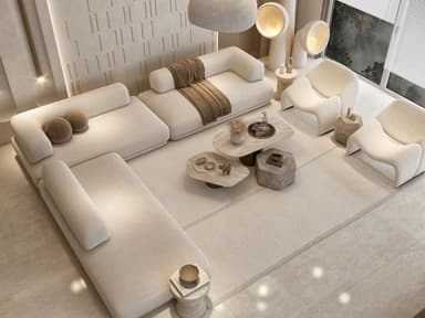 A modular sectional sofa with a low profile and rounded edges. It features a light beige, textured upholstery. The configuration includes multiple seating elements, armrests, and detached ottomans, arranged in a U-shape with an extended chaise section. Two small, round decorative pillows in a brown textured fabric are placed on one section, and a brown woven throw blanket is draped over another. The sofa appears to be designed with a modern, minimalist aesthetic. — 3D model