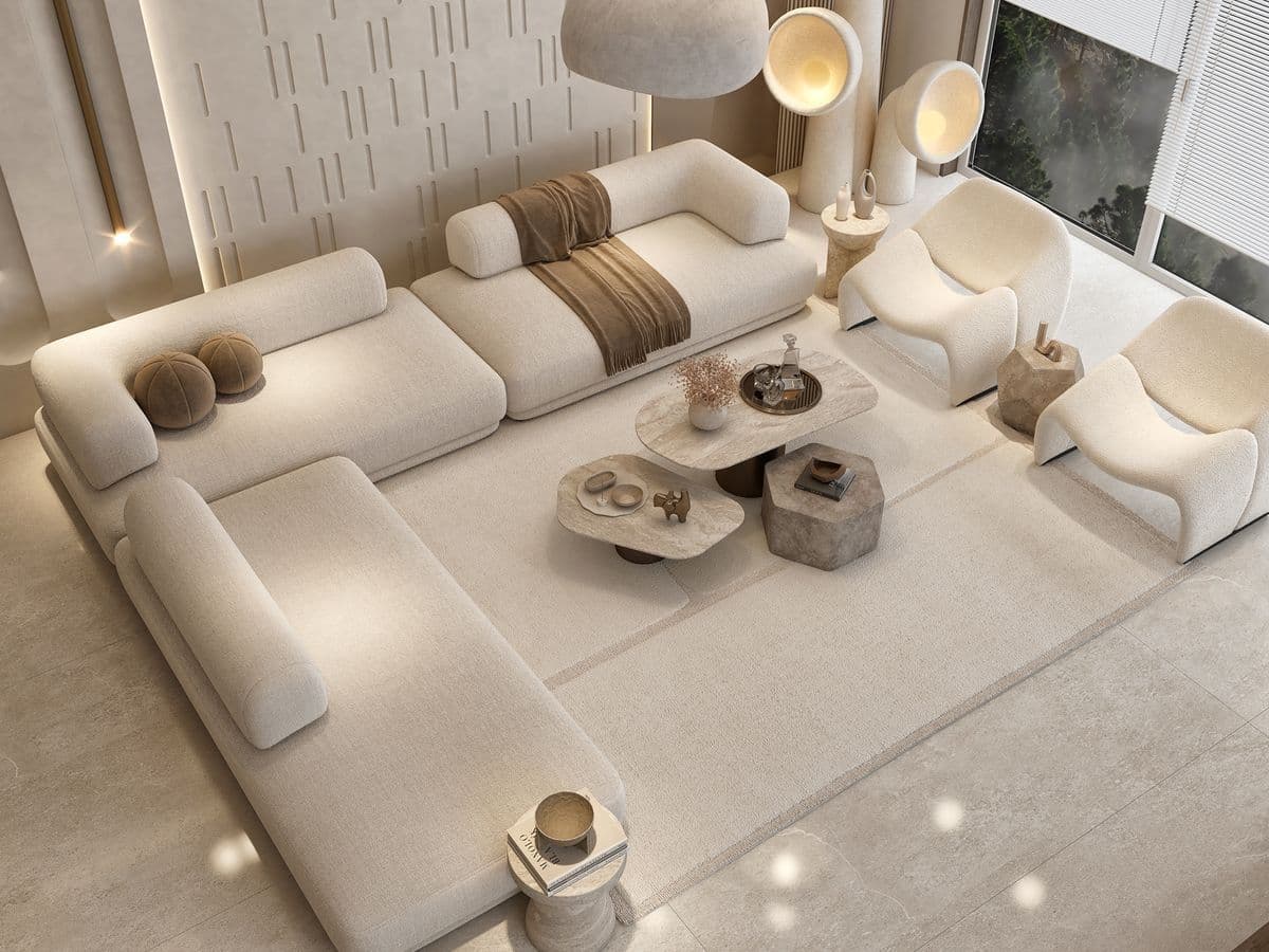 A modular sectional sofa with a low profile and rounded edges. It features a light beige, textured upholstery. The configuration includes multiple seating elements, armrests, and detached ottomans, arranged in a U-shape with an extended chaise section. Two small, round decorative pillows in a brown textured fabric are placed on one section, and a brown woven throw blanket is draped over another. The sofa appears to be designed with a modern, minimalist aesthetic. — 3D model