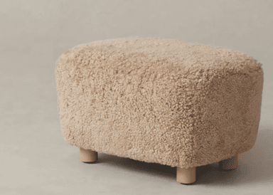 A rectangular ottoman with rounded edges, covered in a textured, fluffy, off-white material resembling sheepskin. It is supported by four short, cylindrical wooden legs. — 3D model